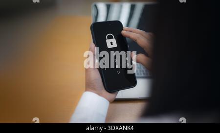 Business person holding a smartphone and entering a secure passcode or pin code to unlock the device for data protection and mobile cybersecurity at a Stock Photo