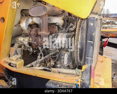 A close-up of the engine and radiator components on an older yellow construction vehicle in an outdoor setting. Stock Photo