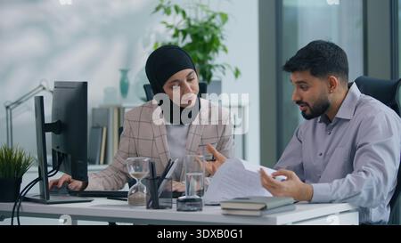 Two muslim business team in office working Islamic group Indian co-workers Arabian colleagues discuss problem bad data information problem difficulty Stock Photo