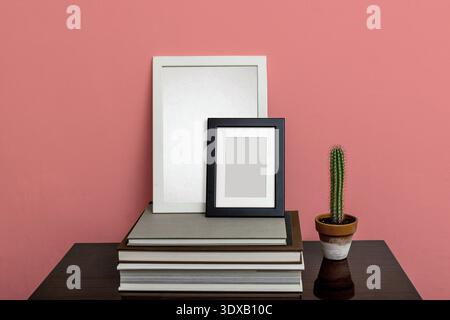 Empty frames with passepartout in A4 and A6 sizes rest on a stack of art books. The larger frame is white, the smaller is black. They are set against Stock Photo