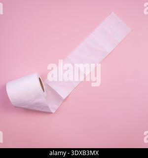 A roll of white toilet paper unrolled on a pink background. The paper is soft and smooth, showcasing its texture and quality. Stock Photo