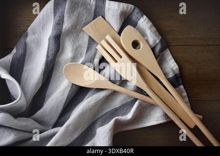 Wooden kitchen utensils on a gray and white cotton cloth on a wooden table Stock Photo