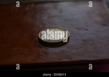 A close-up of a one-euro coin resting on a brown leather surface. Stock Photo