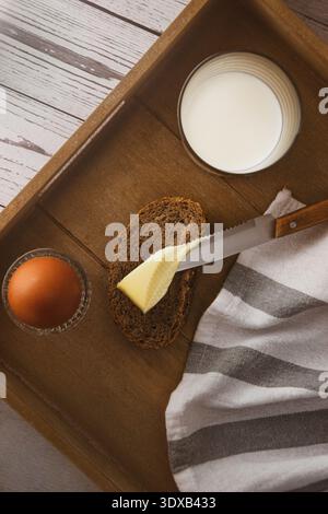 Spreading butter on bread for breakfast with egg and milk Stock Photo