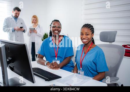 Happy female medical residents smiling working at clinic desk Stock Photo