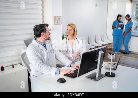 Doctors team working in hospital discussing paperwork and using computer Stock Photo
