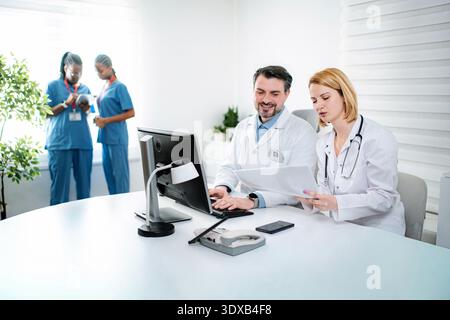 Medical team collaborating on patient records in clinic Stock Photo