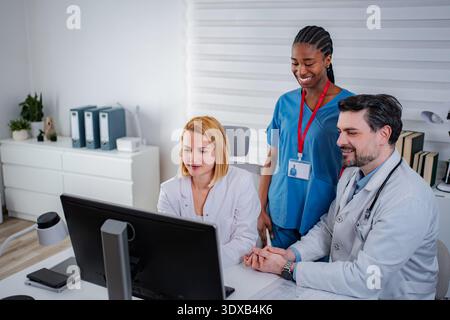 Medical team collaborating discussing patient records on computer Stock Photo