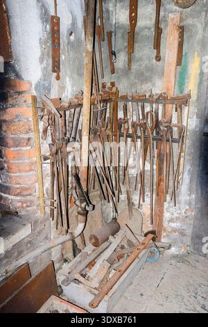Old forge with tools hanging on a wall Stock Photo