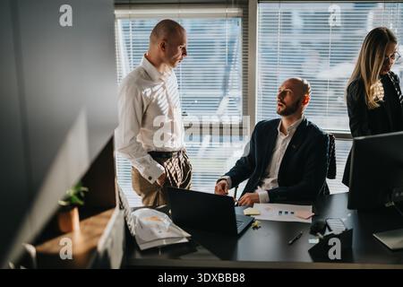 Two business employees discuss strategy at a modern office with laptop and documents Stock Photo