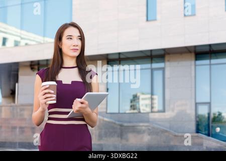 Woman Holding Coffee and Tablet in City Setting During Day Stock Photo