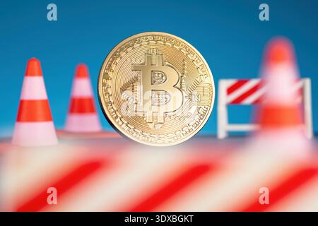 Golden Bitcoin surrounded by traffic cones and barriers, symbolising that cryptocurrencies and blockchain technology are still under construction. Stock Photo