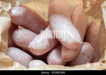 Organic pork sausages, purchased from a butcher, in a brown paper bag background backdrop. Eco friendly biodegradable recycling packaging. Stock Photo