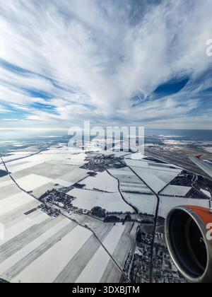 Aerial view from an Easyjet airplane over snowy winter fields and rural villages in Brandenburg Germany, airplane wing and orange jet engine in foregr Stock Photo
