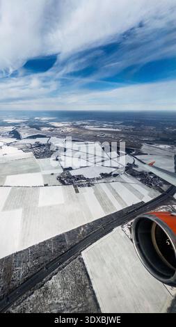 Aerial view from an Easyjet airplane over snowy winter fields and rural villages in Brandenburg Germany, airplane wing and orange jet engine in foregr Stock Photo
