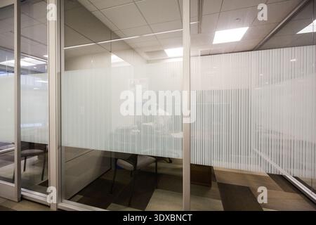 a man at a desk works behind a frosted glass office window Stock Photo