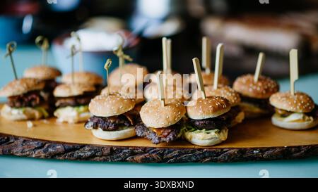 Mini burgers served on buffet table at party catering event. Stock Photo
