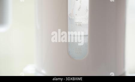 Close up of electric kettle water level window showing measurement marks and condensation droplets. Stock Photo
