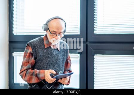 Senior man using tablet and headphones. Stock Photo