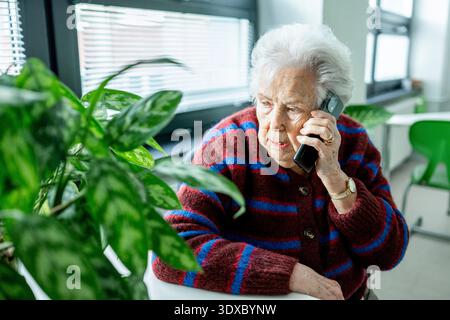 Senior facing phone scams and digital safety. Stock Photo
