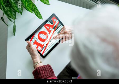 Old person recognizing fake news on digital tablet. Old person recognizing fake news on digital tablet. Rear view. model released Stock Photo