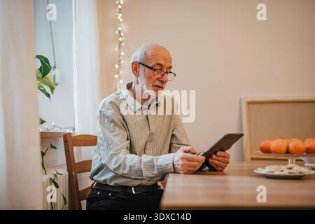 Elderly man using tablet, shopping online. Elderly man using digital tablet, shopping online. model released Stock Photo