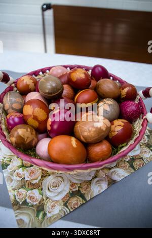 A bag filled with colorful Easter eggs naturally dyed with botanical leaf patterns, placed in a decorative vase. A unique and rustic holiday compositi Stock Photo