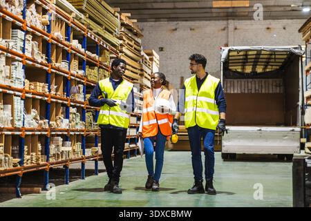 Diverse team of workers walking in lumberyard warehouse Stock Photo