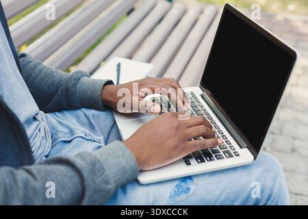 Working on a Laptop While Sitting on a Bench in an Outdoor Area During the Day Stock Photo