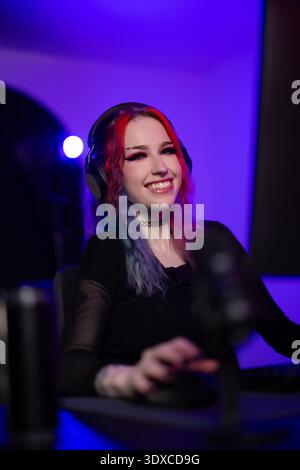 Young woman gaming or streaming online in a vibrant illuminated setting Stock Photo