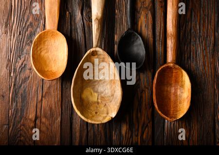 Assorted handcraft wooden spoons arranged on rustic dark wooden background. Kitchen utensils, natural wood texture, cooking tools, farmhouse style Stock Photo