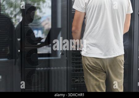 IT technician working on server rack in data center performing hardware maintenance and inspection Stock Photo