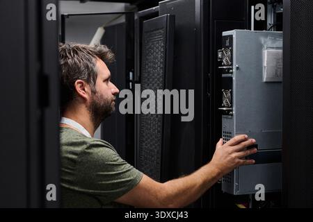 Data center technician performing server maintenance in a rack-filled server room Stock Photo