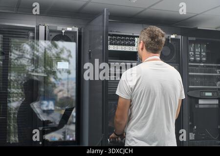IT technician working on server rack in a modern data center checking network hardware and equipment Stock Photo
