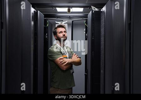 IT technician inspecting servers in a data center server room with racks and network equipment Stock Photo