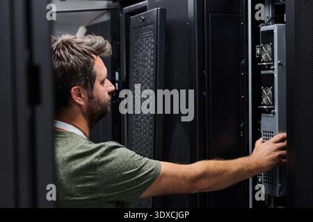 It technician inspecting servers in a data center server rack for maintenance and network support Stock Photo