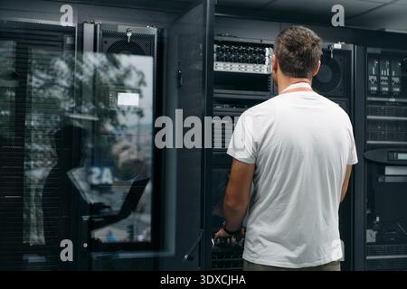 Data center technician checks server hardware in a modern server room for network maintenance and monitoring Stock Photo