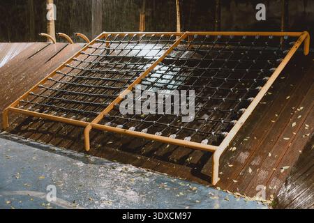 Wet wooden bed frames with metal springs on rainy deck in Shanghai, China Stock Photo