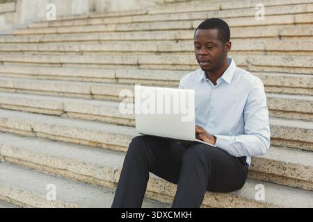 Man Working on Laptop While Sitting on Stone Steps During Daylight Hours Stock Photo