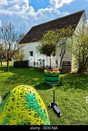 Springtime rustic garden with white barn and egg shaped planter of blooming pansies during Easter time in the spring Stock Photo