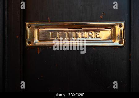 Brass letterbox on a black door in Florence, Italy, showing the sign for letters during daytime Stock Photo