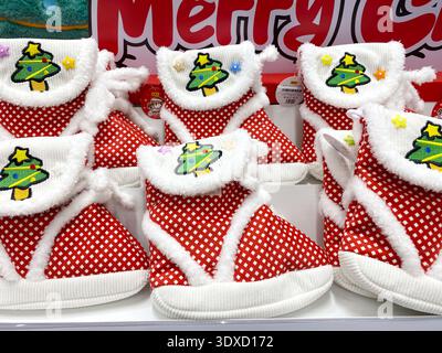 Pattaya, Thailand - November 20, 2025: Red Christmas slippers with white trim and tree design are showcased in a joyful holiday atmosphere Stock Photo