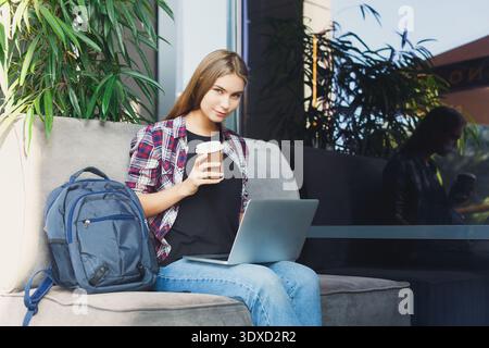 Young Woman Works on Laptop With Coffee in Cozy Cafe Setting Stock Photo