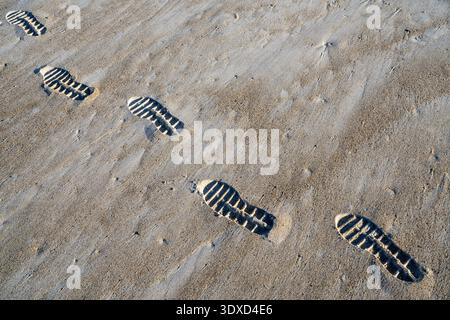 Shoe Prints in the Sand on the Beach on a Sunny Day Stock Photo