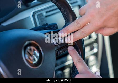 Close up of hand pressing buttons on car steering wheel Stock Photo
