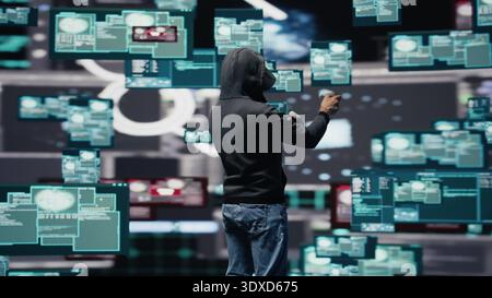 Man uses virtual reality headset for system corruption and password cracking, cyber intelligence define this tech driven theft. Intrusion and threat alerts reveal dangerous hacking. Camera B. Stock Photo