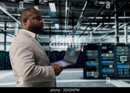 Server hub system administrator using AI software on laptop to monitor equipment energy consumption. IT professional managing supercomputers in server hub using artificial intelligence tech Stock Photo