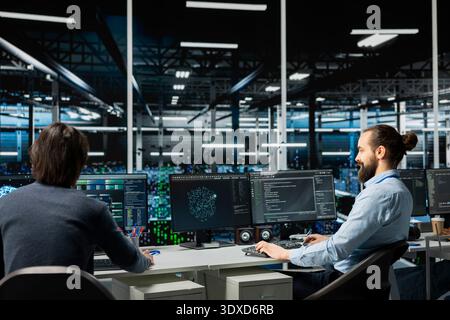 Team of data center programmers working together in office, managing AI systems for uptime and efficiency. IT staff members using artificial intelligence technology on computers in server hub Stock Photo