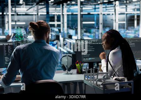 Technicians doing brainstorming, working in server farm with hardware supporting data mining. Data center coworkers talking, doing maintenance on racks storing blockchain records Stock Photo