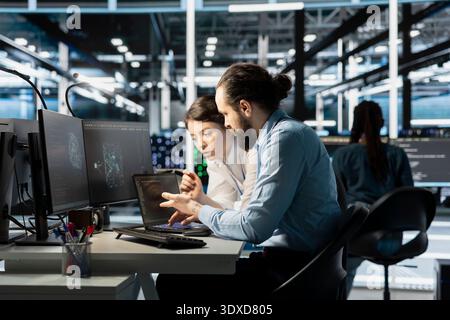 Team of software developers in data center integrating AI driven automation tools. Server farm IT professionals doing brainstorming, using artificial intelligence deep learning models Stock Photo